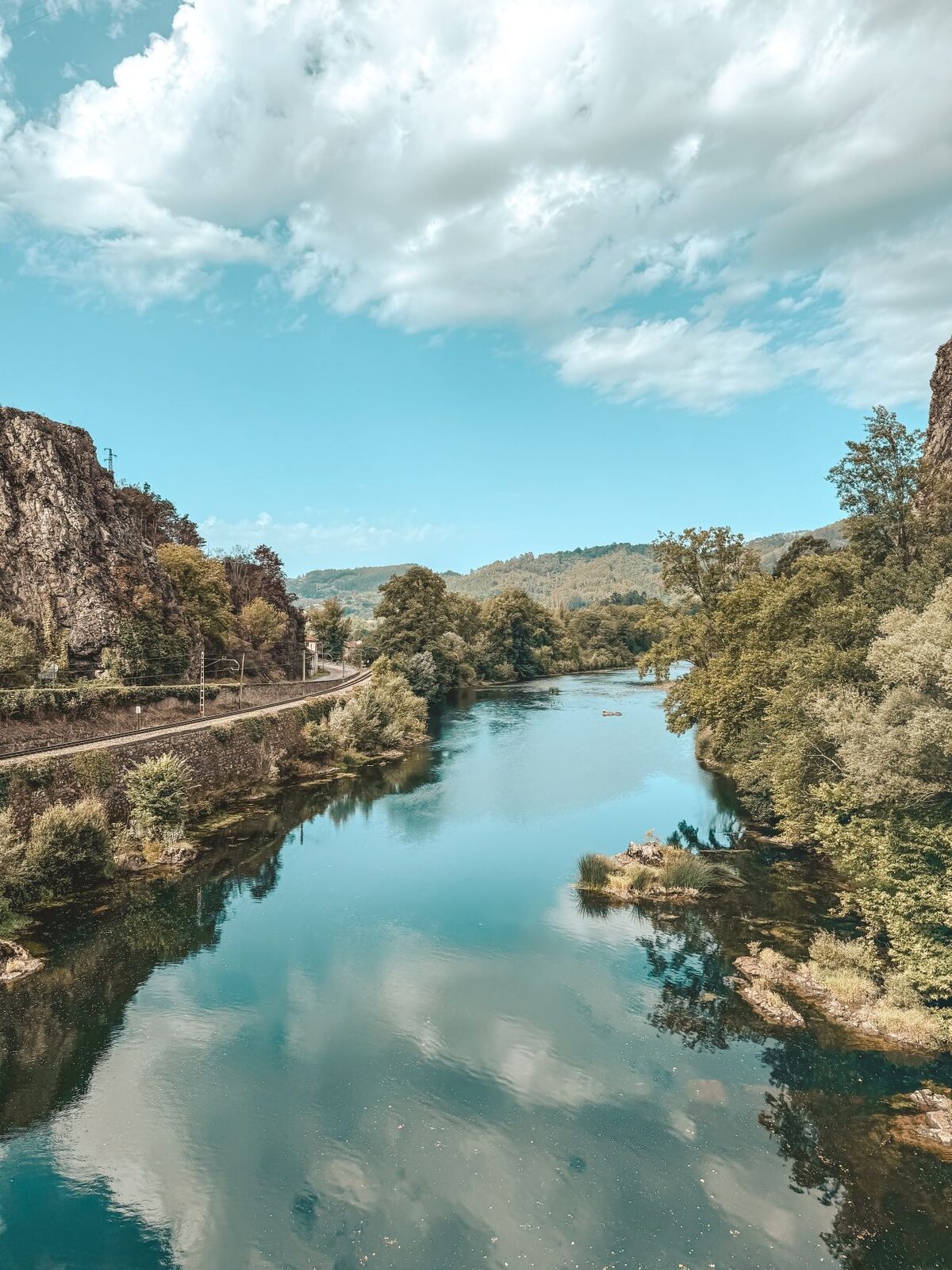 Ein ruhiger Fluss zwischen Felsen, in dem sich der Himmel spiegelt